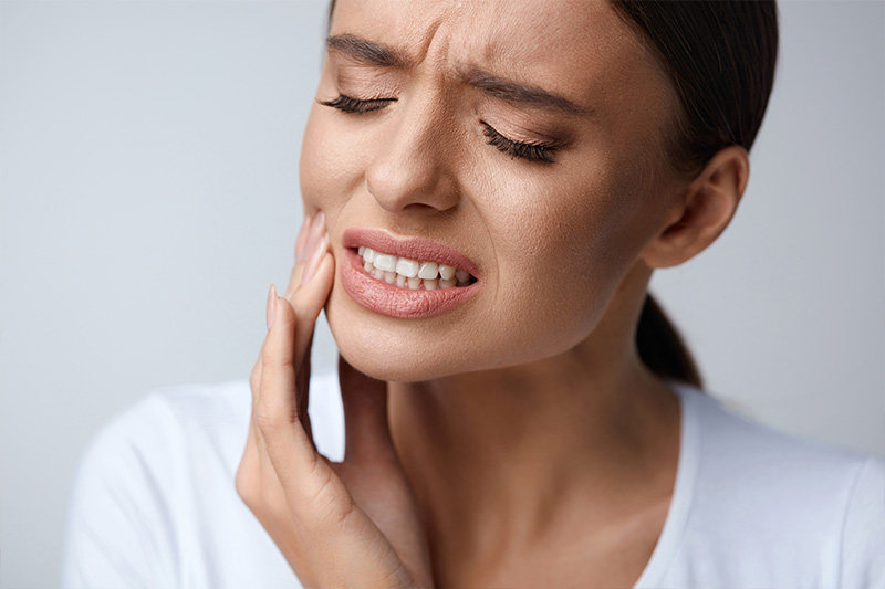 Woman with tooth pain in need of an emergency dentist in Morgan Hill